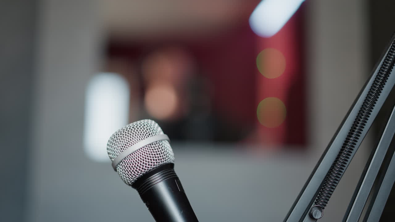 toma de primer plano de un micrófono con un fondo borroso, enfatizando los detalles del micrófón mientras crea un fondo suave y fuera de enfoque. el fondo borroso sugiere un entorno de estudio