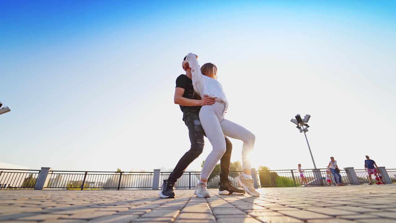 Street dance of young couple. Dancing pair performing freestyle dance in outdoor urban setting. Fashionable dance outdoors.