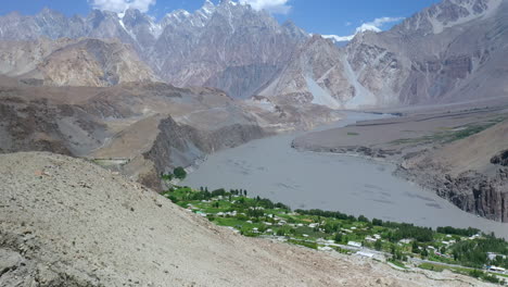 amplia toma aérea de conos de passu y pueblo o ciudad en pakistán con el camino del glaciar, titulando hacia arriba la toma de drones