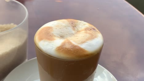 spoon of sugar is melting and dissolving inside the cappuccino cup
