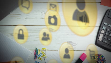 Animation-of-multiple-digital-icons-against-close-up-of-office-equipment-on-wooden-table