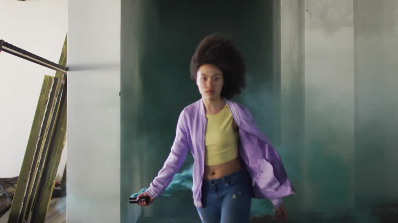 Woman walking, raising handheld, emitting teal smoke and spawning emojis around her for marketing