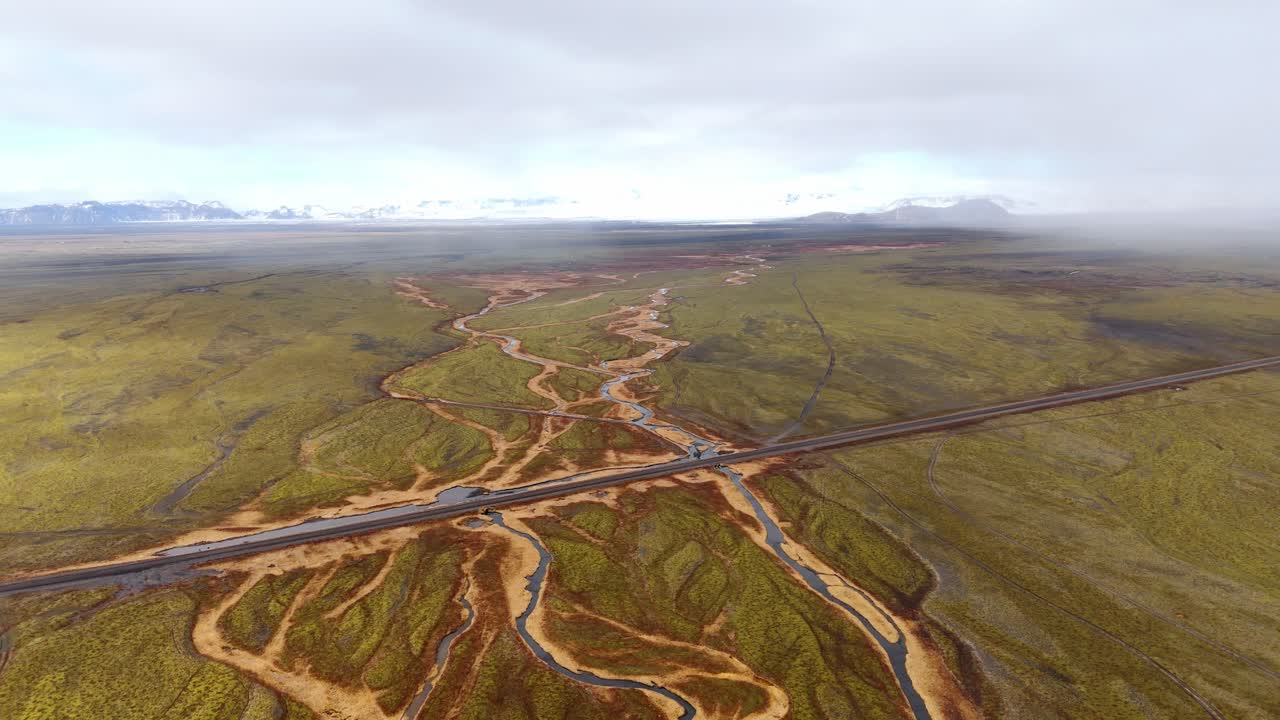 fotografía aérea de un vasto paisaje islandés con ríos trenzados y una carretera solitaria