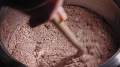 revolviendo los ingredientes del pastel de avena choco rico en proteínas con una cuchara de madera en una olla