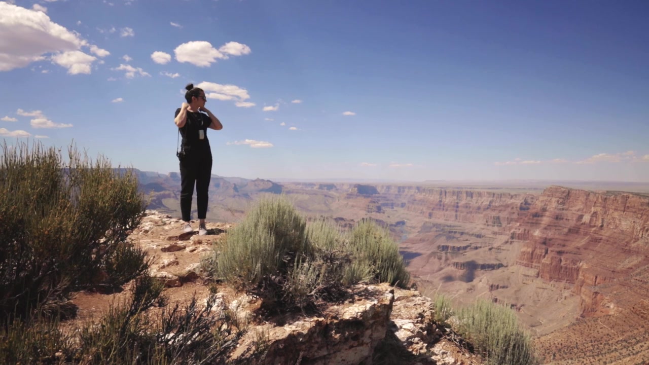 Young woman with cameras standing at the Grand Canyon.