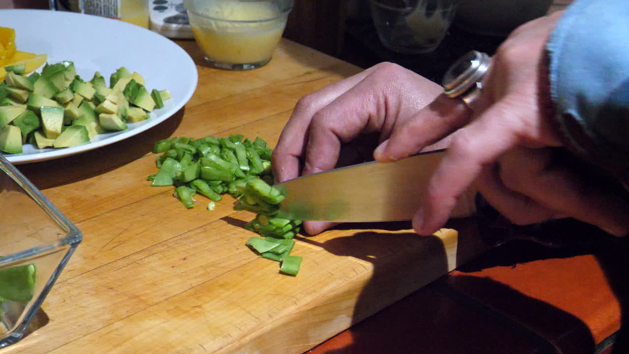 A chef preparing and cutting vegan ingredients and vegetables with a knife in a kitchen for a healthy meal