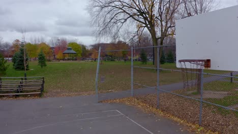 Drone-Pasando-Frente-A-Una-Red-De-Baloncesto-En-Un-Parque-Público-En-Un-Día-Gris-De-Otoño-En-Montreal