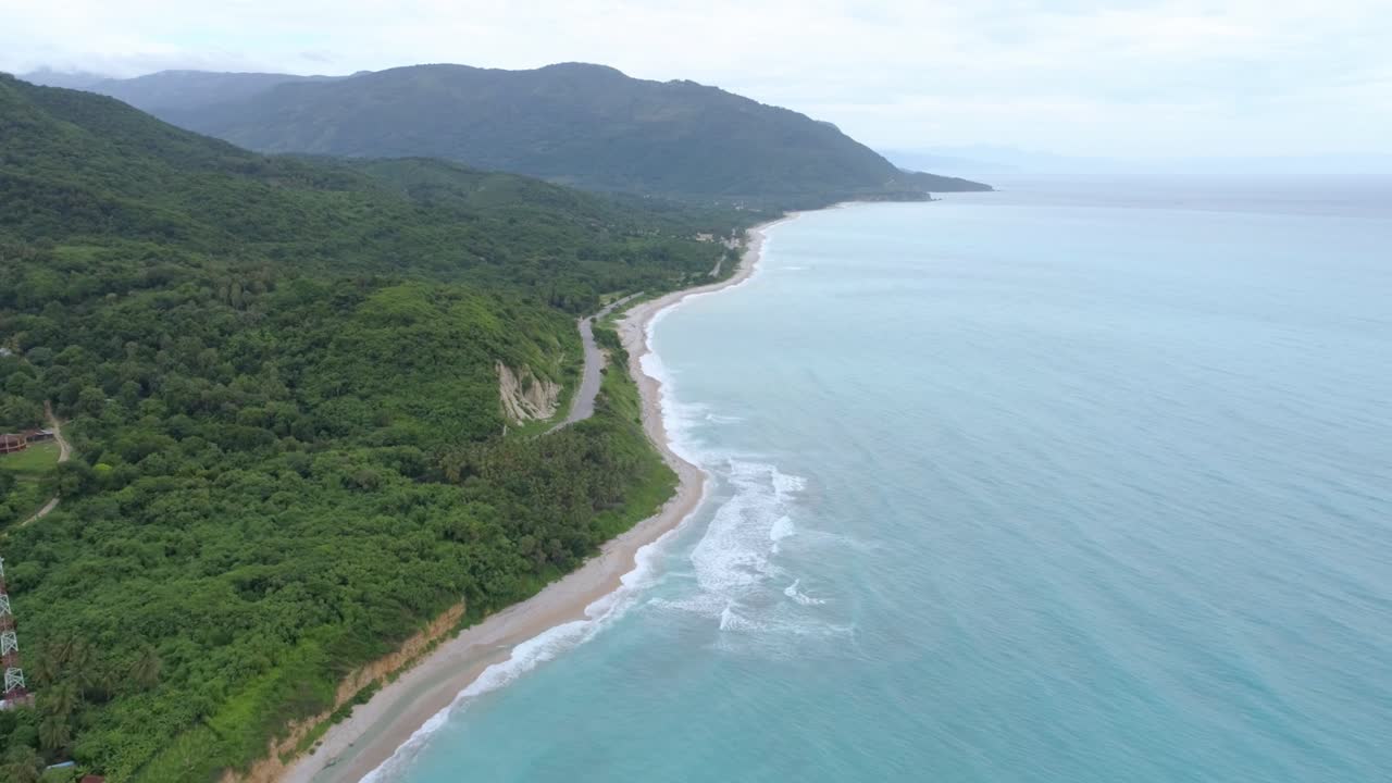 vuelo hacia atrás con drone con vista a la hermosa playa los patos en barahona, aguas azules día nublado, hermosas montañas