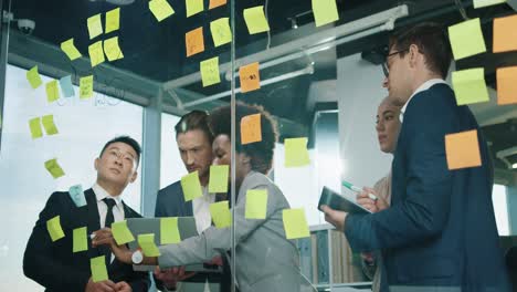 close up view of multiethnic business people group working in a modern office while writing on glass in a cabinet with sticky notes 6