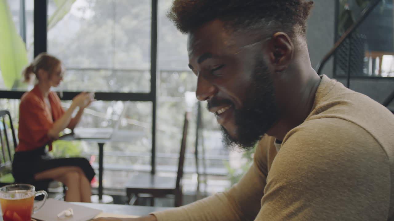 Uomo di colore sorridente e allegro che guarda la fotocamera in un bar