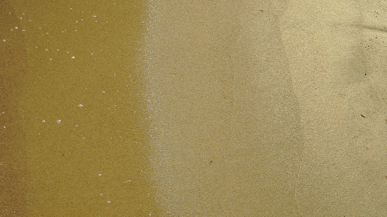 cámara lenta, vista de la orilla del mar, espuma del agua vertida en la arena, arena y agua en la costa