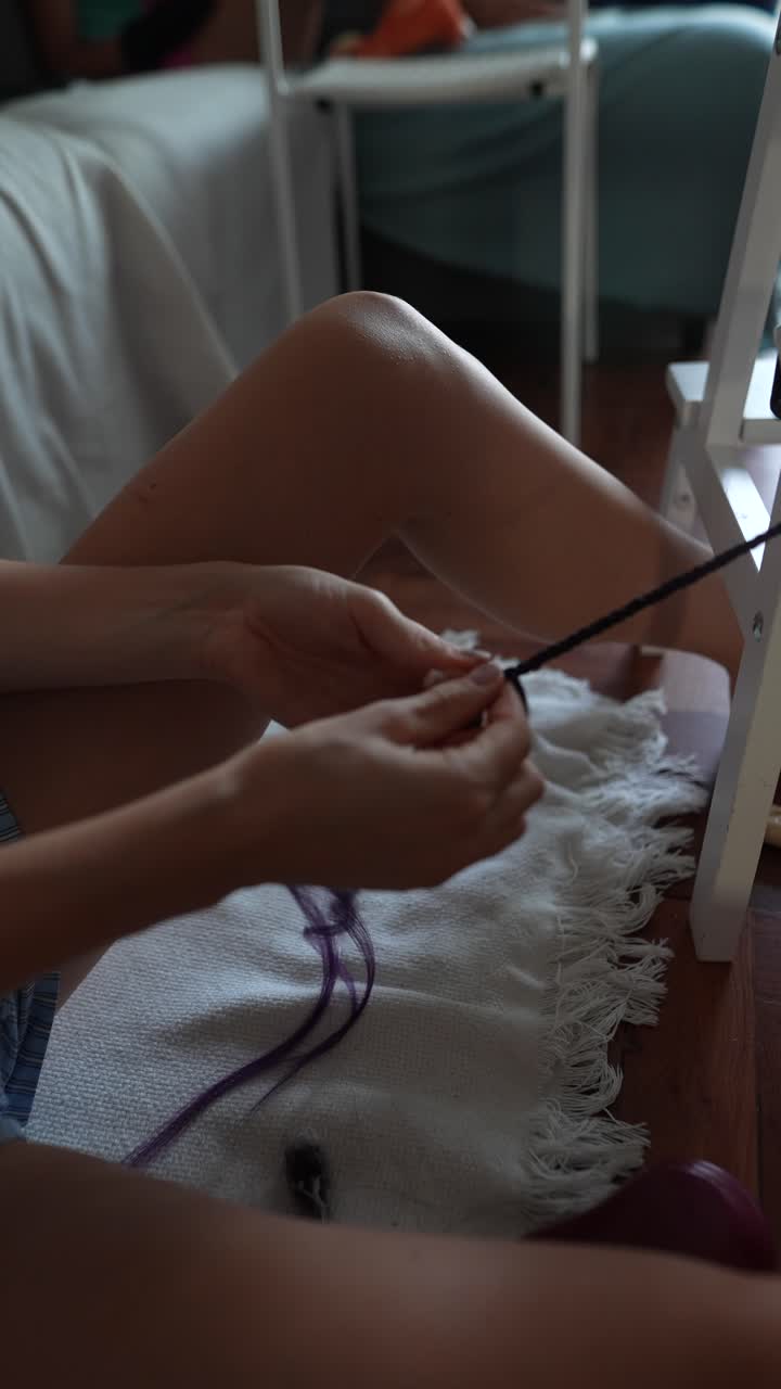 Woman weaving yarn with a weaving frame