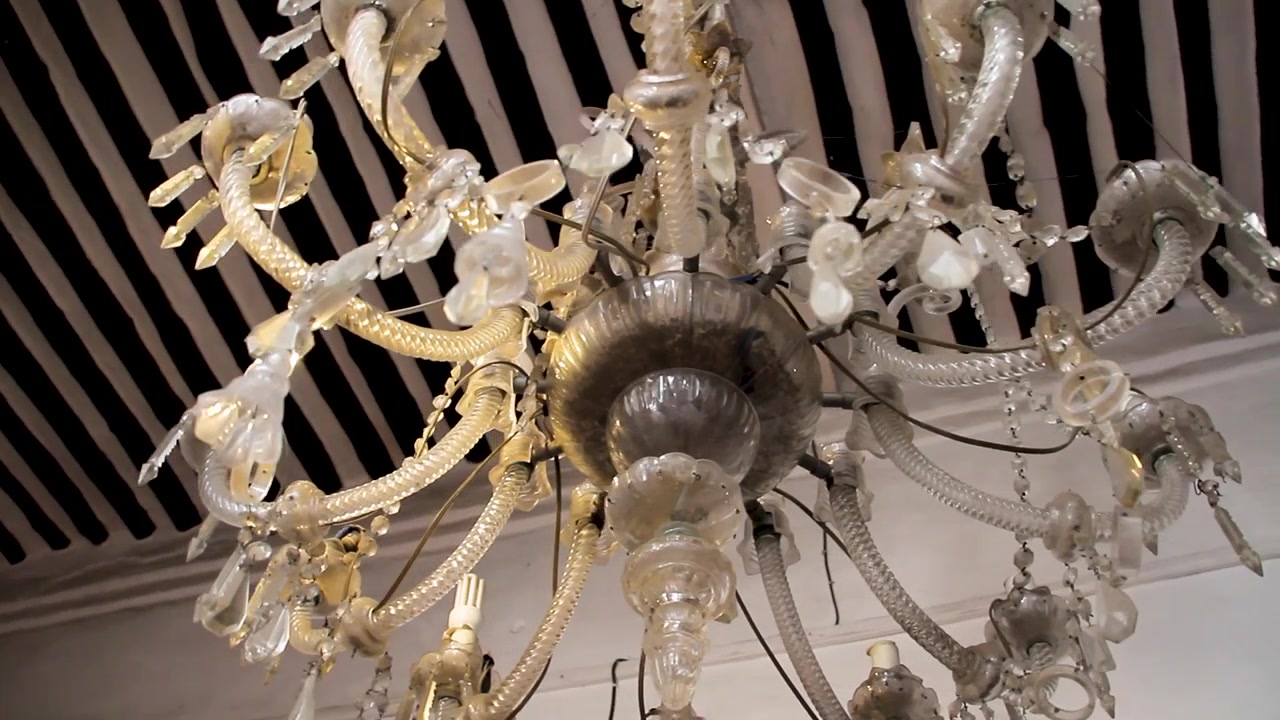 Lampadario di cristallo vintage ornato appeso a un soffitto a strisce.