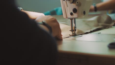 primer plano de las manos del diseñador de moda cosiendo tela usando una máquina de coser
