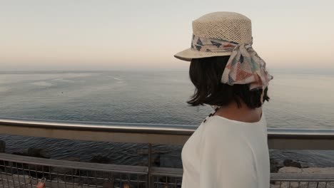 A-young-girl-in-her-20s-turning-around-on-a-dock,-smiling-and-sending-kisses-towards-the-camera