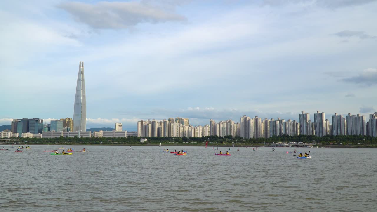 롯데월드타워가 도시 스카이라인을 지배하는 서울 한강에서 카약과 패들 보딩을 즐기는 사람들