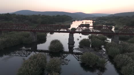 Old-railroad-bridge-over-the-seasonal-Komati-River-in-South-Africa,-early-morning-aerial-shot