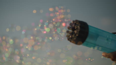 close-up of a plastic bubble gun releasing a stream of colorful bubbles under a clear sky. playful moment, highlighting the vibrant bubbles and the simple joy of play in an outdoor setting