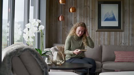 beautiful woman at home sits on the couch and reads a book in the living room, static shot