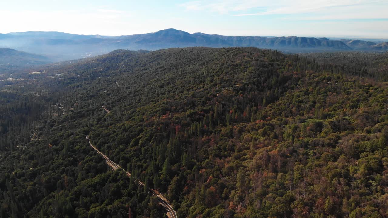 toma aérea de 4k de una carretera que serpentea a través de las montañas y los bosques de california