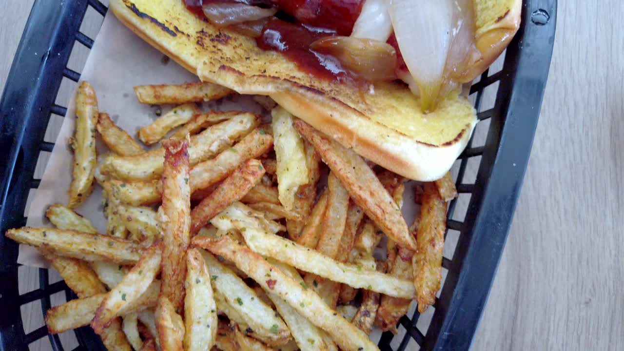 Detailed shot of a hot dog with grilled onions, ketchup and fries on the side, perfect for fast food concepts