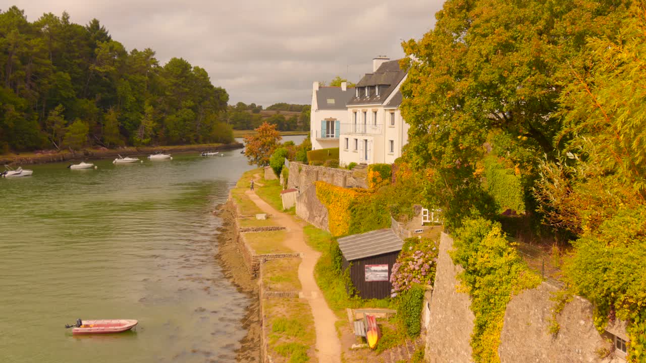 Charming riverside in Le Bono, Brittany, with boats and lush greenery