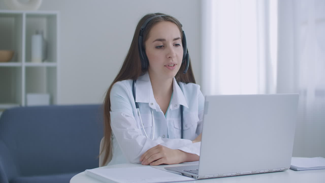 una asistente médica lleva una bata blanca con auriculares llamando a un paciente distante por computadora portátil. un médico hablando con un cliente usando una aplicación de computadora de chat virtual. concepto de servicios de atención médica remota de telemedicina.