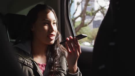 Asian-woman-talking-on-smartphone-while-sitting-in-the-car