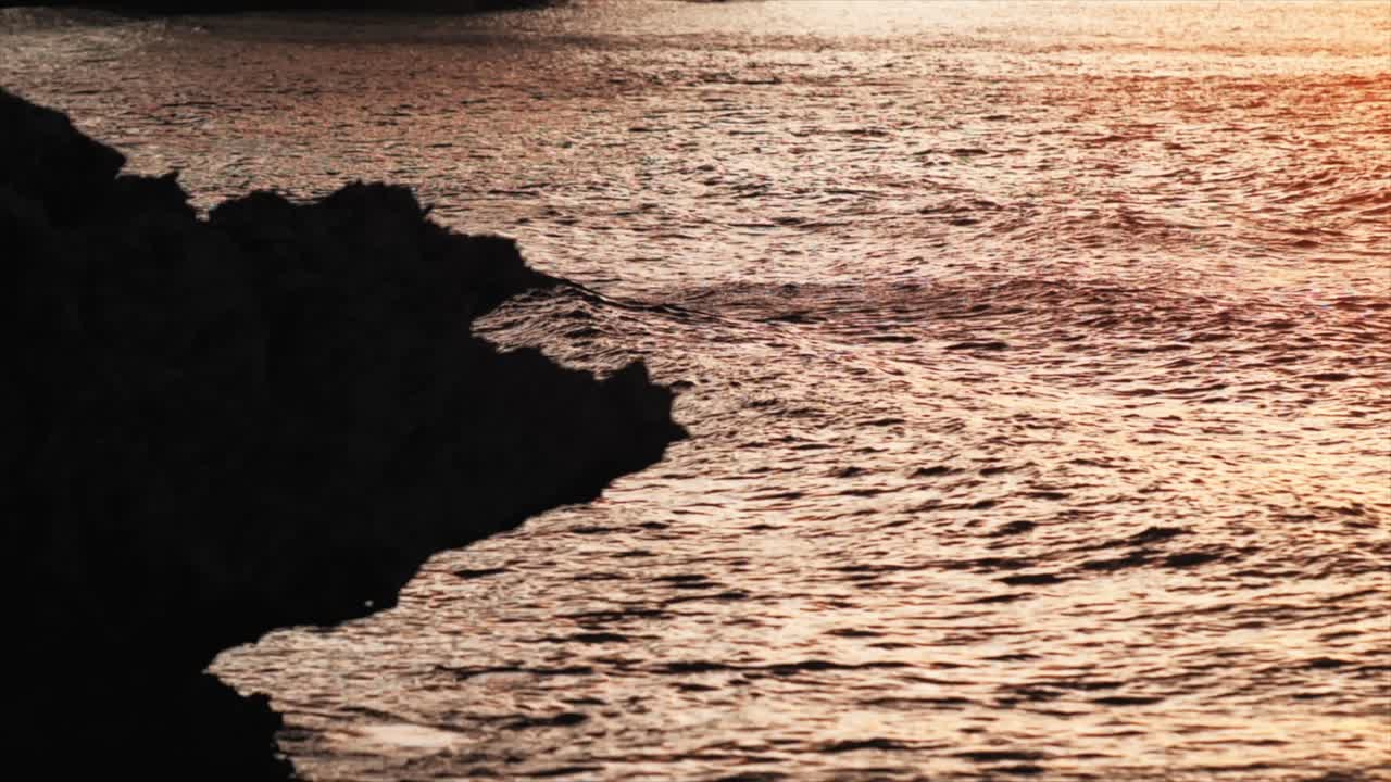 сломо волн, приближающихся к скалам на солнце