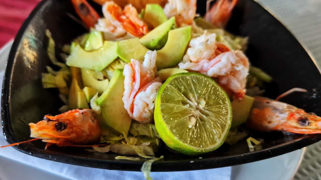 Healthy meal with greens, vegetables and protein served in stylish dish with black tray base, shrimp seafood salad
