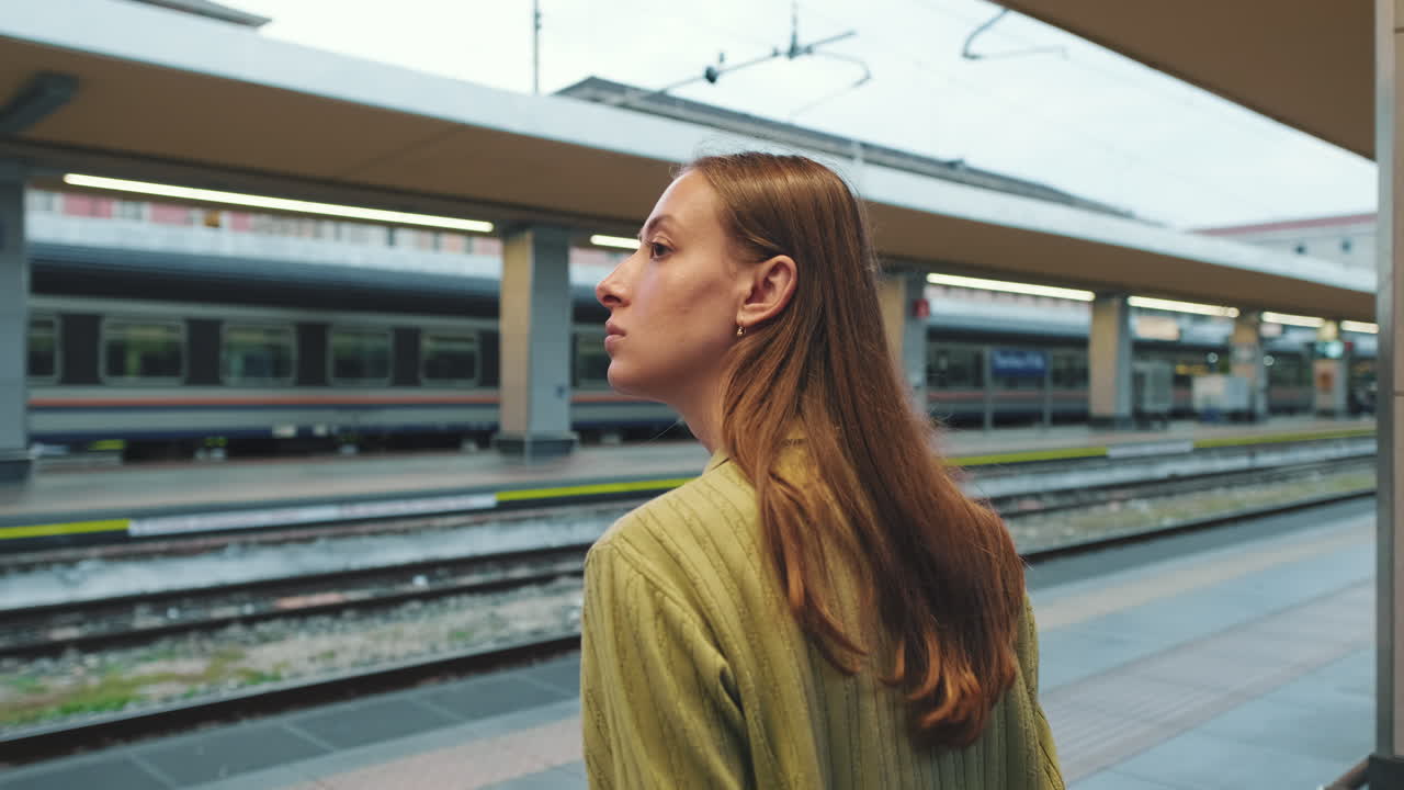 Giovane donna in attesa sulla banchina di una stazione ferroviaria