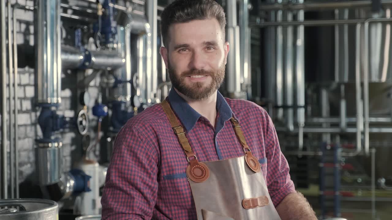 Giovane birraio che indossa un grembiule di pelle trasporta un barile di birra artigianale in un birrificio moderno.