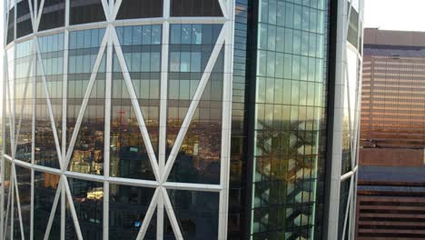 Aerial-view-close-to-reflecting-windows,-revealing-traffic-on-the-streets-of-Calgary,-Canada---tilt,-drone-shot