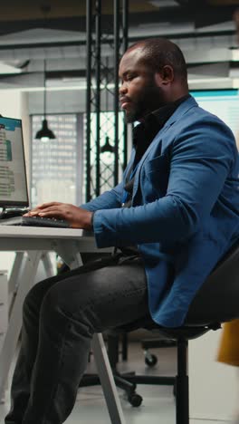 vertical video black male analyst focused on it company development with digital tools