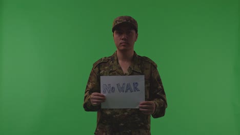 asian male soldier holding white paper with slogan no war while standing on the green screen background