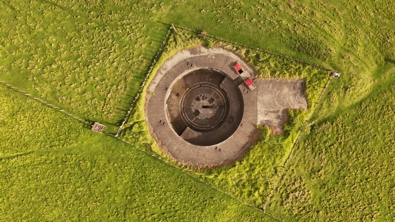 Stony Batter, historic WWII coastal defence fortress on Waiheke Island, gun emplacement surrounded by lush green fields, New Zealand. Aerial top-down view, drone ascending
