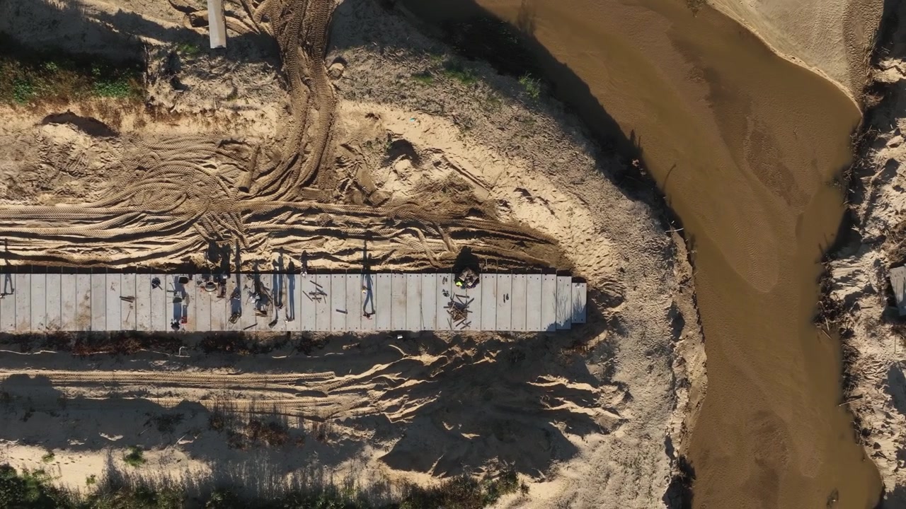 Construction workers walk on concrete top to water canal being built