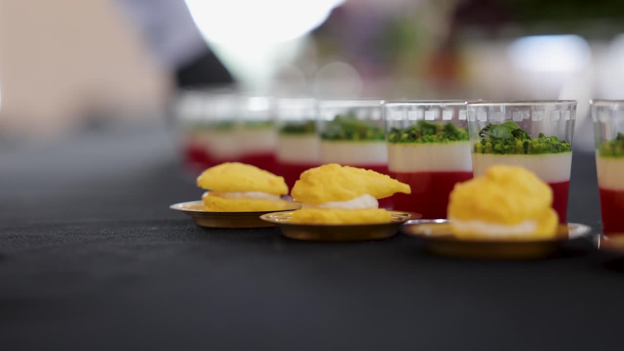 Waiter placing finger food upon catering table among other delicious assortments