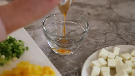 woman pouring sauce into bowl for mixing in slow motion