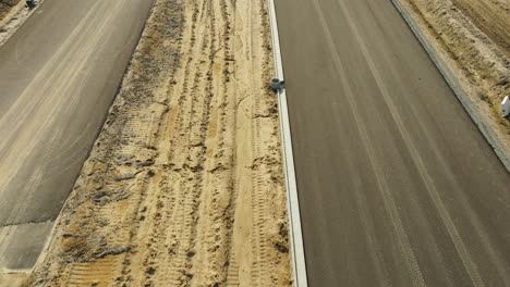 Roadway-under-construction-beside-fields-and-buildings