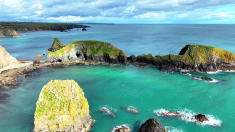 drone flying over emerald sea over small islands with hidden sea caves and inlets irelands coast and wild beauty