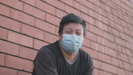 ecuadorian worker with mask talking and gesturing while sitting outdoor - medium static shot in slow motion