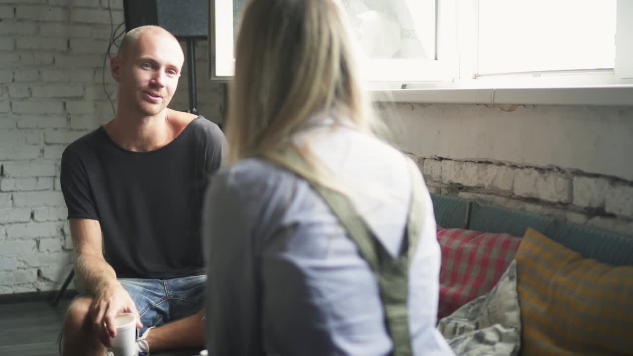 hombre y mujer colegas están sentados en el sofá en la oficina y hablando entre sí, sonriendo y riendo