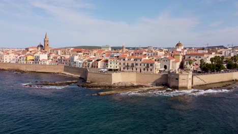 Steady-4K-drone-clip-of-the-edge-of-the-town-of-Alghero-in-Sardinia,-with-a-big-cathedral-and-the-wall-next-to-the-sea