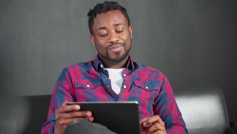 man using tablet on couch