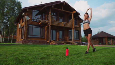 mujer en la hierba haciendo yoga en el fondo de una hermosa casa. el concepto de un estilo de vida saludable