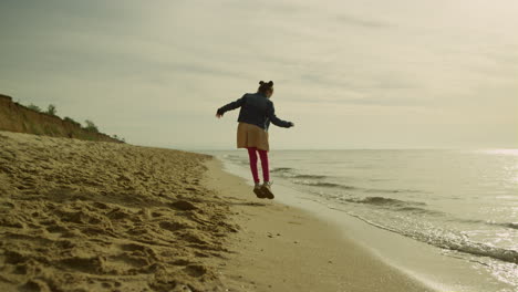 niña jugando en la playa en la naturaleza del mar. niño alegre saltando en la línea de la playa de arena.