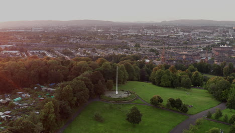 una foto de un dron giratorio del asta de la bandera en la parte superior del parque de la reina, glasgow