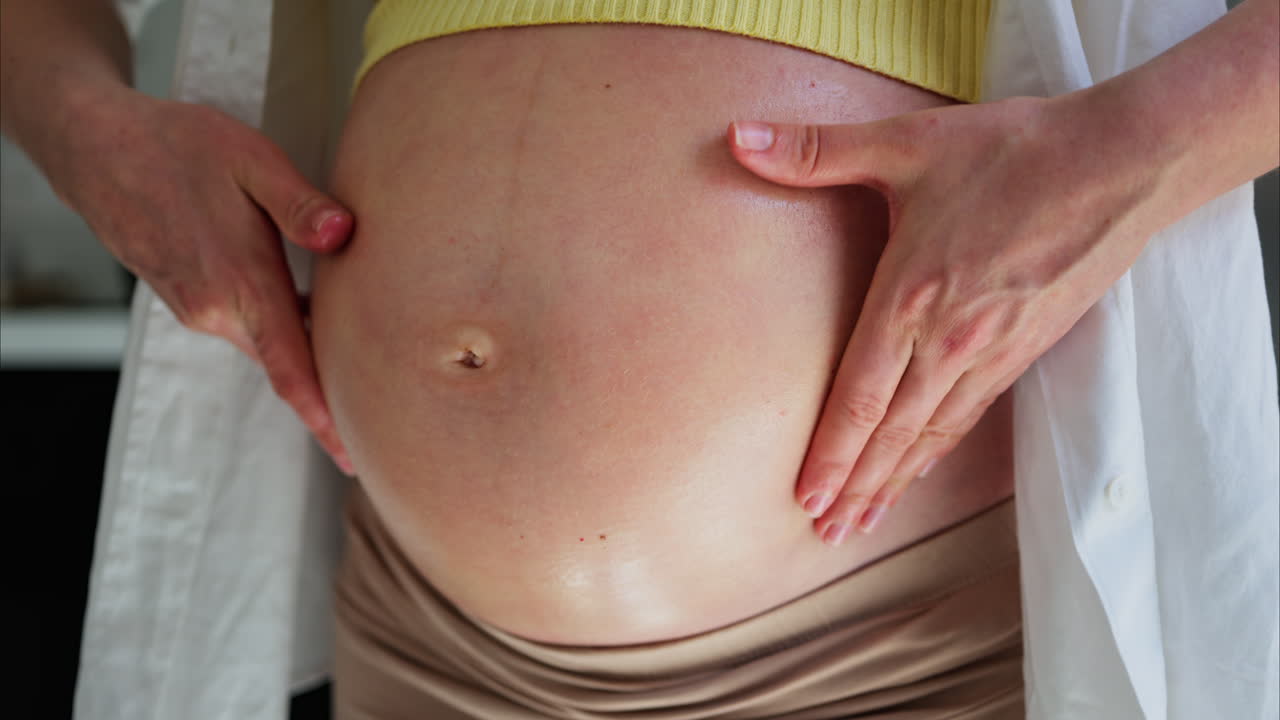 Close de uma mulher massageando a barriga de grávida com óleo