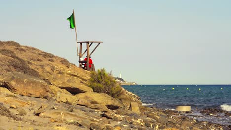 Pequeña-Torre-De-Vigilancia-De-Salvavidas-Con-Una-Bandera-Verde